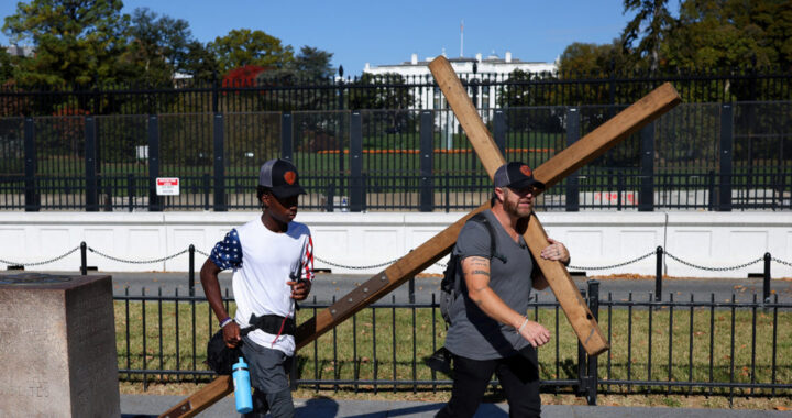 A man wheels a large wooden cross near the White House in Washington as a reporter records a broadcast during the U.S. presidential election on Nov. 5, 2024, Election Day. (OSV News photo/Daniel Cole, Reuters)